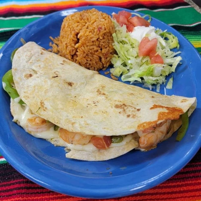 A shrimp quesadilla with melted cheese, green peppers, rice, and a side salad on a blue plate.